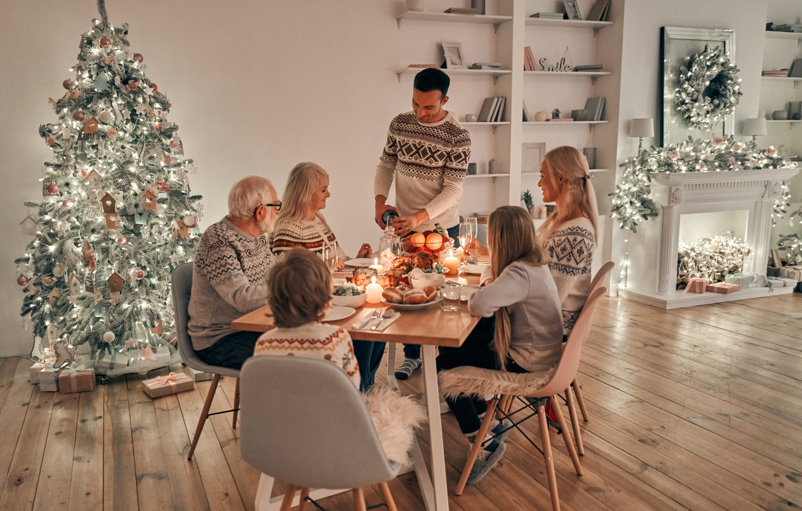 The beautiful family having dinner on the christmas tree background